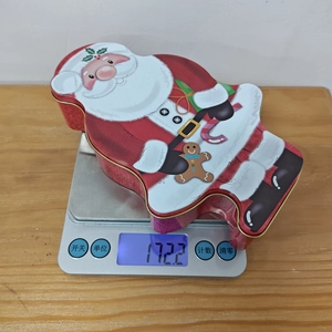 Detailed view of Christmas Santa tin box being weighed on a digital scale for accuracy