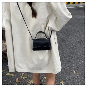 Chic black minimalist leather crossbody bag styled on a street photography model
