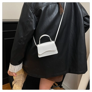 Close-up of a white micro crossbody bag on a model with a black leather jacket background