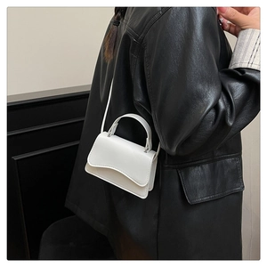 Micro white leather handbag with round handle shown on model in black jacket