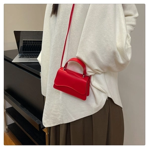 Close-up of stylish red leather mini square crossbody bag with wavy flap and top handle