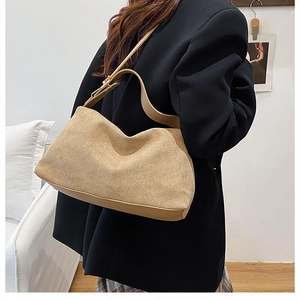 Close-up of minimalist suede shoulder bag with smooth leather trim on a model