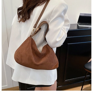 Detail of brown matte suede hobo bag with gold hardware worn on white casual blazer
