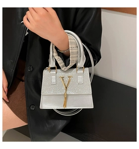Detail of silver sequin handbag featuring golden V logo and elegant fringe tassel