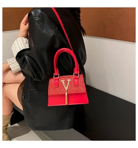 Detail of red small handbag with sequin finish, golden V logo and stylish tassel charm