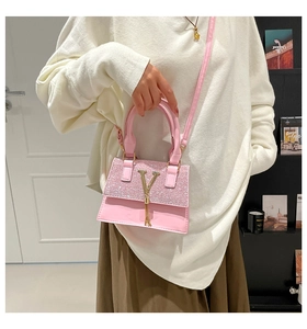 Pink glitter handbag detail with gold V logo and tassel held by model in room