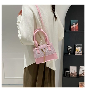 Close-up of pink rhinestone handbag with gold V-metal detail and top handle shown on model