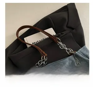 Dettaglio borsa tote in denim floreale con catena, manico in pelle e ciondolo a perla