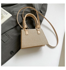 Macro detail of beige sequined handbag with shimmering texture and leather handle