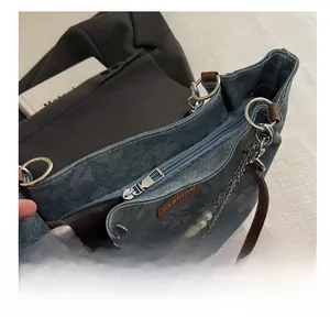 Dettaglio della borsa in denim con cerniera in metallo liscia e catena di perle