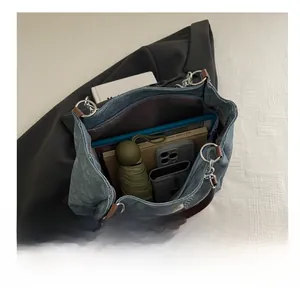 Interno spazioso della borsa tote in denim con catena che mostra oggetti quotidiani