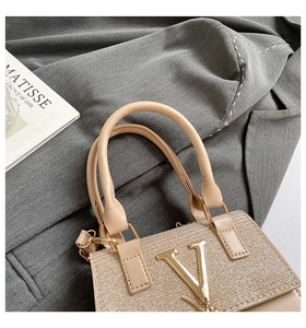 Detailed close-up of champagne gold sequin handbag with V-logo and premium leather handle