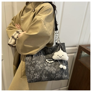 Close-up of gray floral tote bag featuring silver chain straps and a plush cloud charm