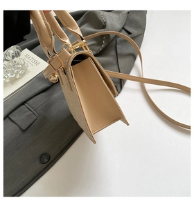 Detail of beige textured fabric and leather stitching on a chic crossbody shoulder bag