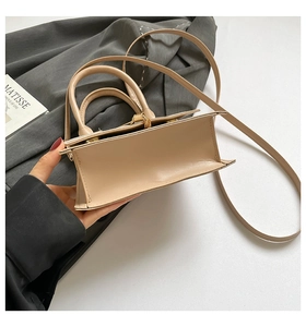 Detail of a beige leather mini handbag showing trapezoid side structure and gold metal hardware