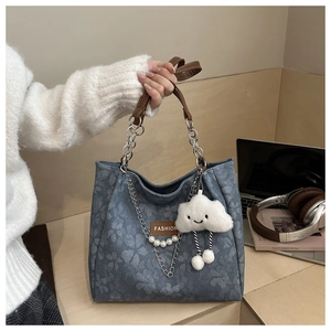 Detail of blue floral tote bag with brown leather handles and pearl pendant charm