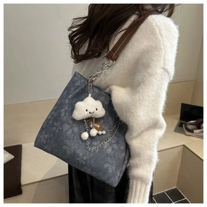 Detail view of floral blue tote bag with silver chain straps and plush cloud charm accessory