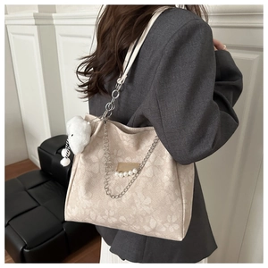 Detail view of jacquard floral tote bag with pearl chains and plush bear charm