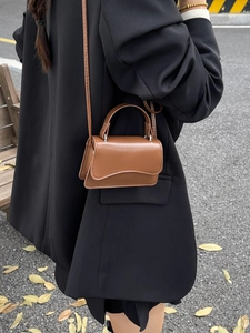 Brown leather crossbody mini square bag shown with a stylish black coat in street style