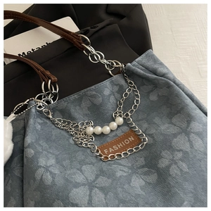 Macro shot of blue floral denim tote with silver chains and white pearl accents
