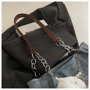 Detail of blue denim tote bag with silver chain strap and white plush pendant
