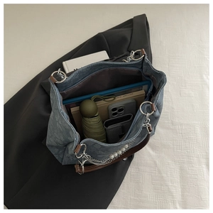 Macro view of blue denim tote bag interior showing large capacity and pearl chain detail
