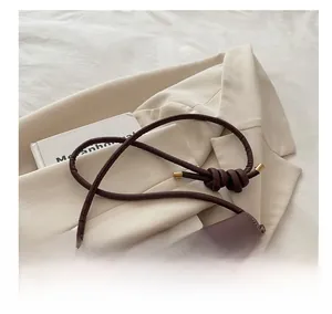 Dettaglio borsa in pelle marrone cioccolato con tracolla a nodo e finiture dorate