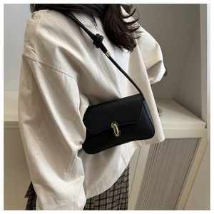 Detail van een minimalistische zwarte schoudertas met een gouden rechthoekige gesp erop