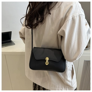 Detail of minimalist black crossbody bag with gold oval twist lock on matte leather