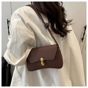 Detail of a dark brown vintage shoulder bag with curved bottom and gold hardware
