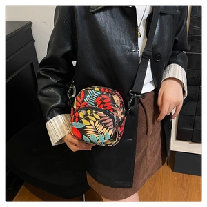 On-body view of lightweight crossbody bag with colorful leaf print and dual zip compartments