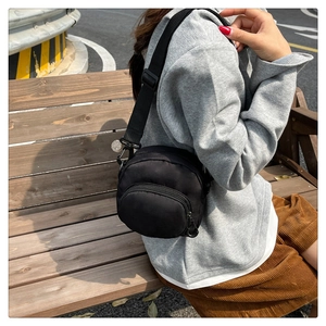 Detail of lightweight black waterproof crossbody bag on model in outdoor setting