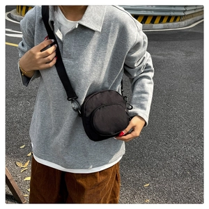 Detail of a black canvas crossbody bag with double zip pockets and adjustable strap