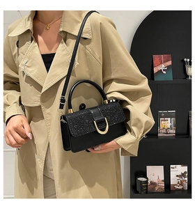 Black leather handbag with glitter flap and golden horseshoe buckle on a model