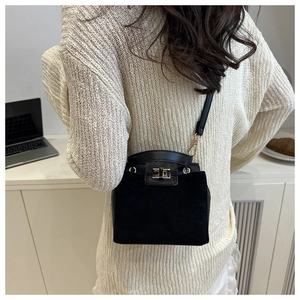 Close-up of black crossbody bag with gold turn-lock closure on female model at the office