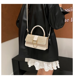 Detail of cream crossbody bag with sequin flap and gold D-ring buckle on a model