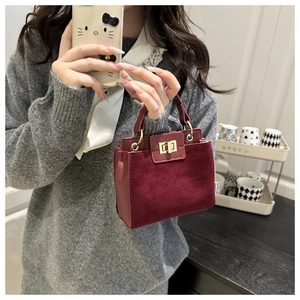 Detail of burgundy suede and PU leather handbag featuring a gold metal twist lock closure