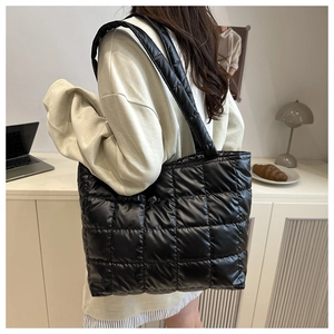 Vue détaillée du sac fourre-tout noir matelassé avec finition brillante et motif à carreaux
