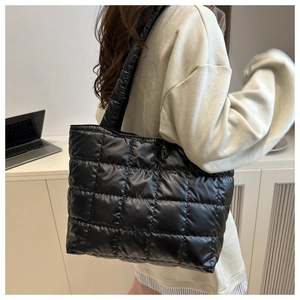 Detailed view of black quilted tote bag with large square stitching on nylon fabric