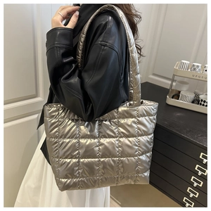 Detail of silver metallic quilted tote bag worn over the shoulder with a black leather jacket