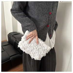 Detail of elegant white 3D rose lace evening clutch bag held by model for wedding party