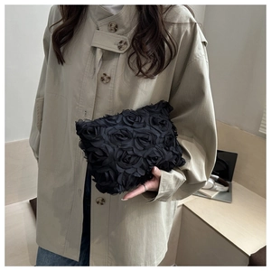 Detail of a black handbag featuring dense 3D fabric rose flower textures on textile material