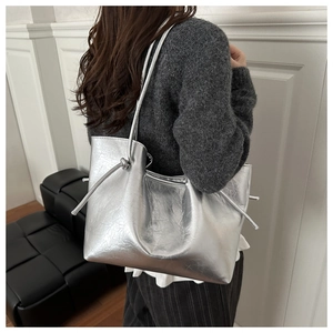 Detail view of metallic silver tote bag with knotted strap and wrinkled texture design
