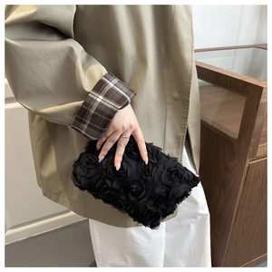 Detail of elegant black 3D rose fabric clutch evening bag with rich floral textures