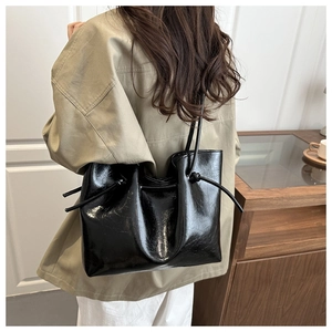 Detail of a shiny black leather tote bag with pleated texture and stylish shoulder strap