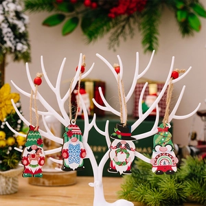Détail de quatre gnomes de Noël en bois suspendus sur un support décoratif blanc