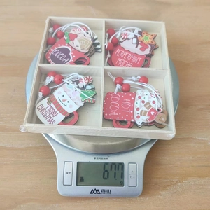 Balance numérique affichant le poids de 67,7g des ornements de Noël en bois en boîte