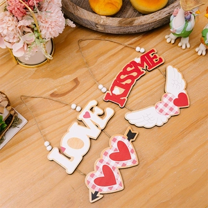 Détail de suspensions en bois LOVE et KISSME avec motifs de cœurs et cordes en jute