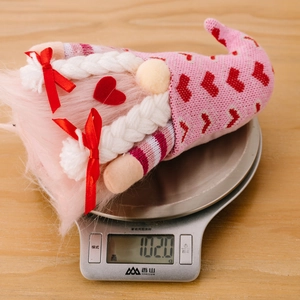 Dettaglio dello gnomo rosa di San Valentino con cappello a cuori su una bilancia