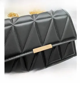 Detail view of black quilted crossbody bag with gold rectangular lock and chain strap